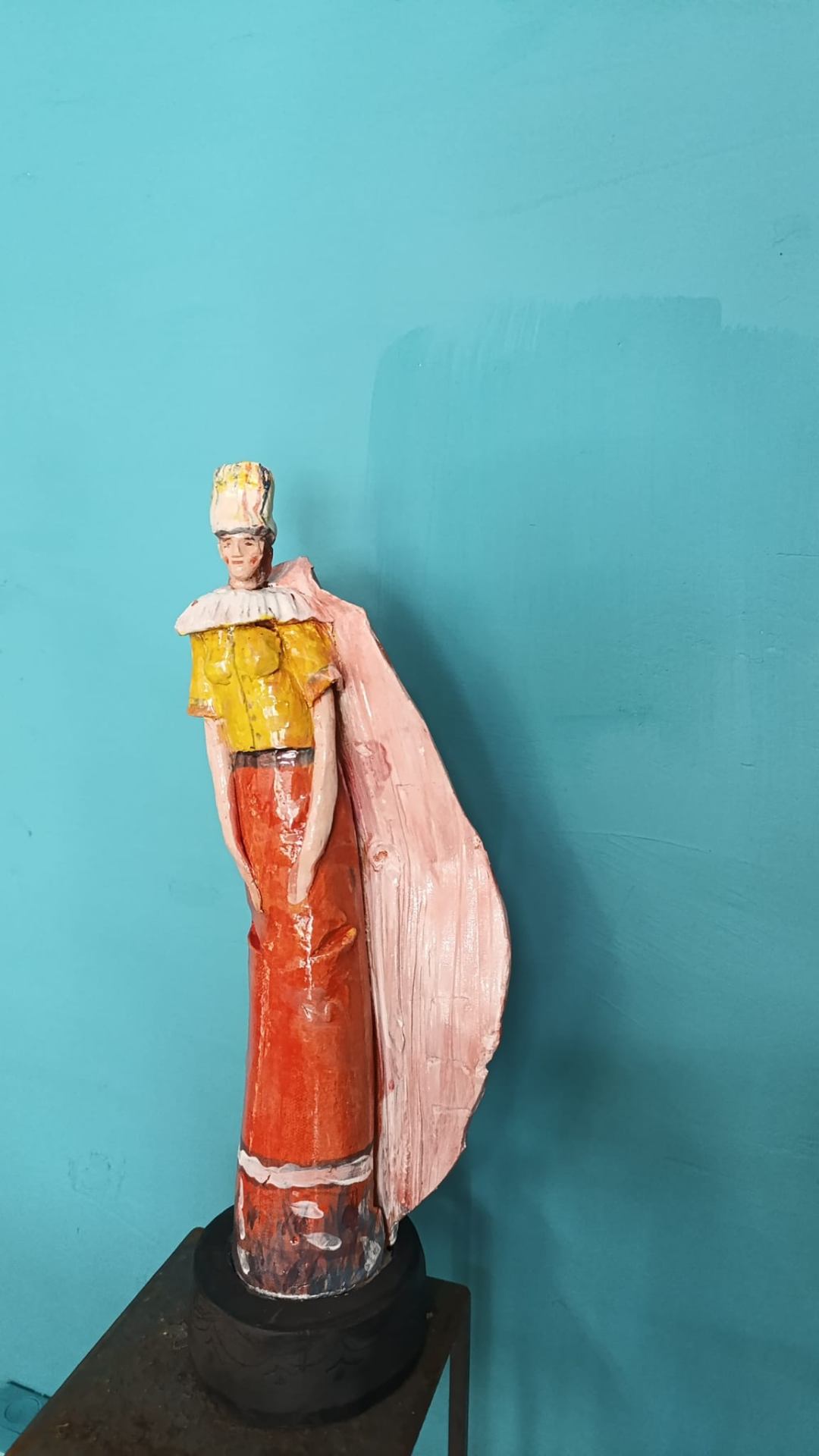 Figura con mantello rosa e abito arancione
