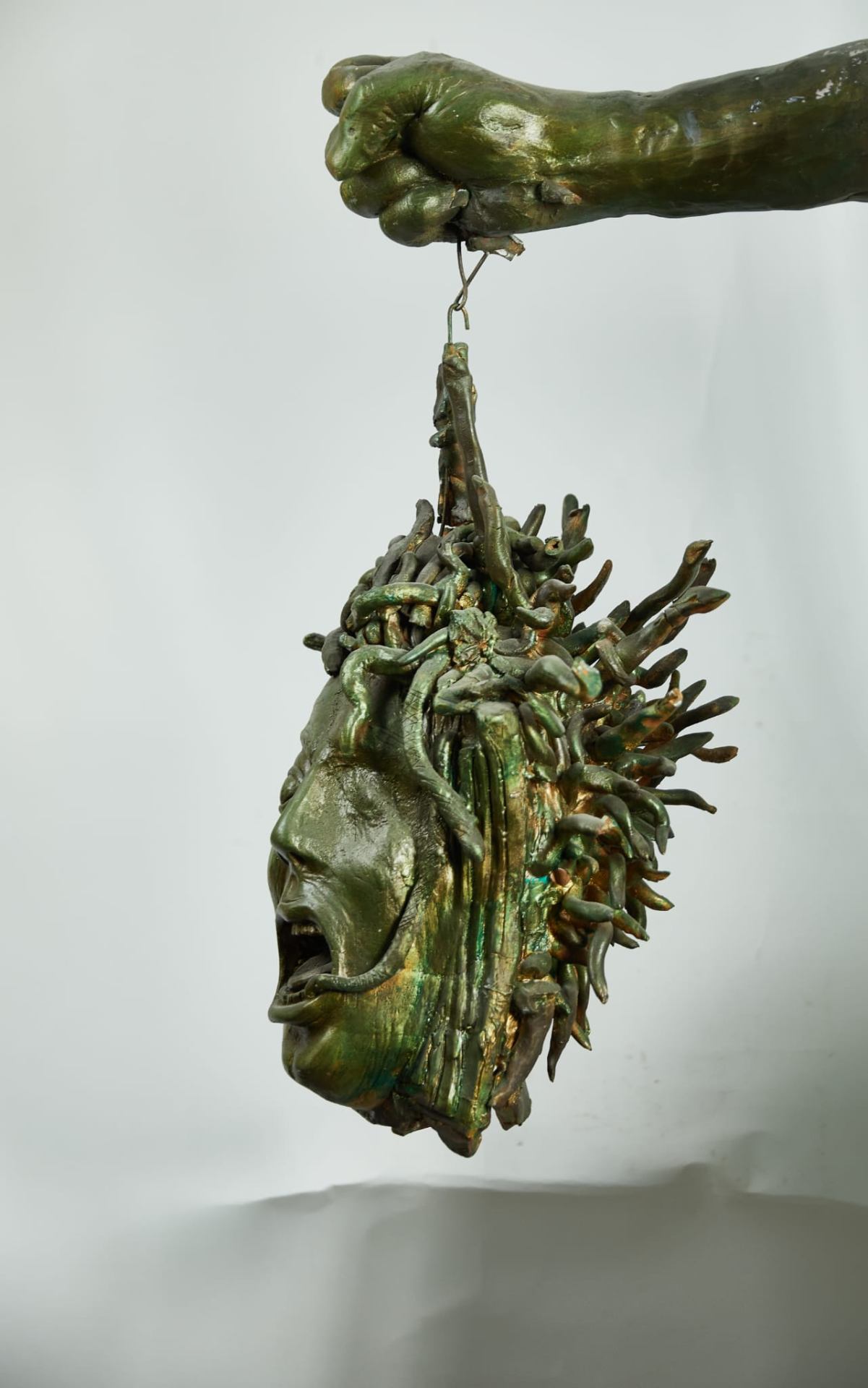Testa di Medusa Raku verde tenuta da una mano scultorea
