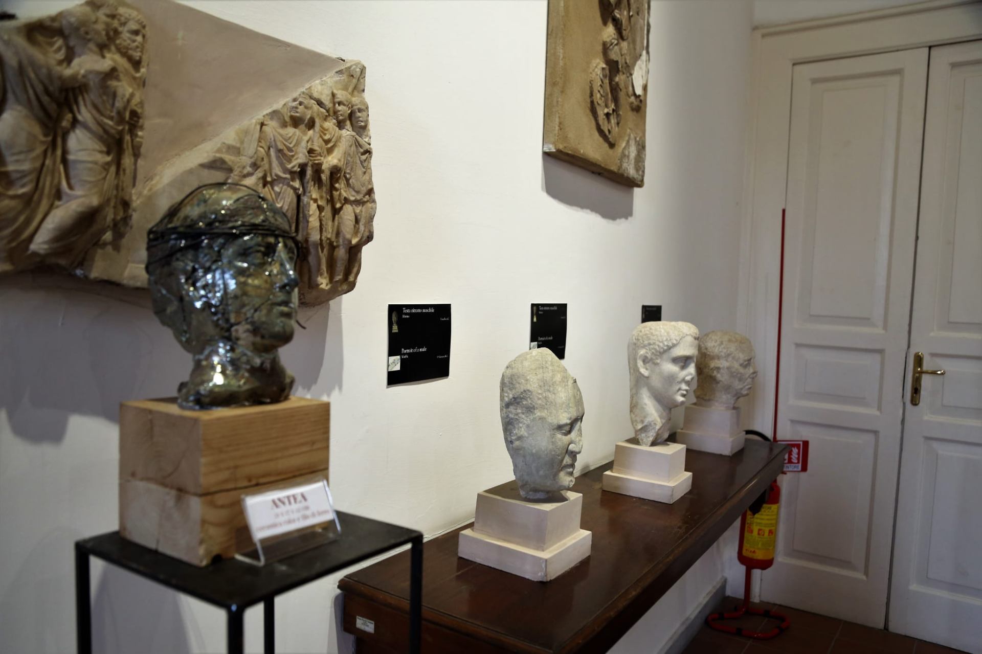 Busto Raku Antea con elmo accanto a teste antiche