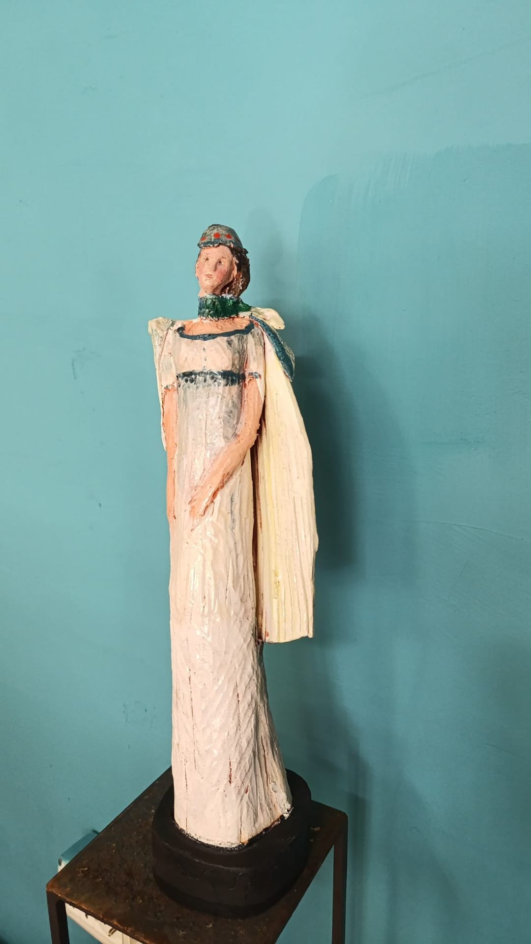 Figura femminile in abito chiaro su sfondo turchese