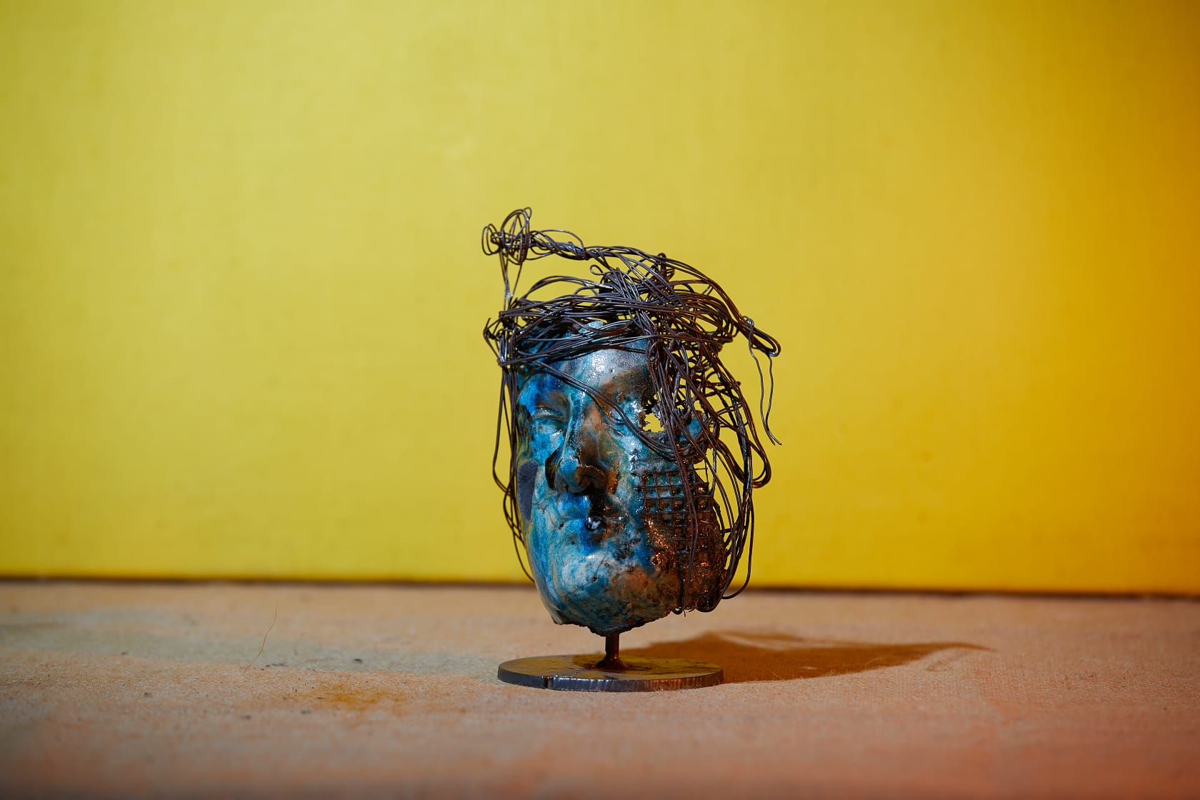 Volto Raku blu con capigliatura di filo metallico su fondo giallo