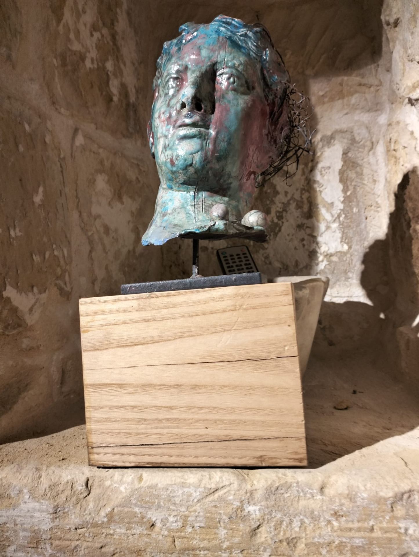 Volto Raku in nicchia di pietra con riflessi blu e rossi