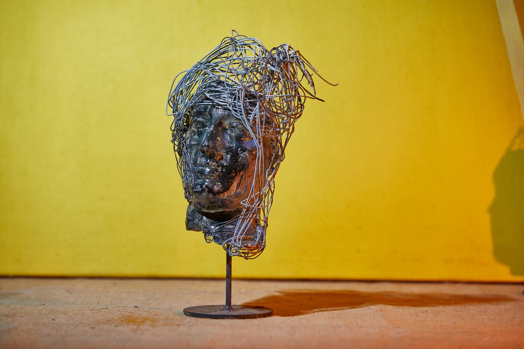 Volto Raku metallizzato con capigliatura di filo su fondo giallo