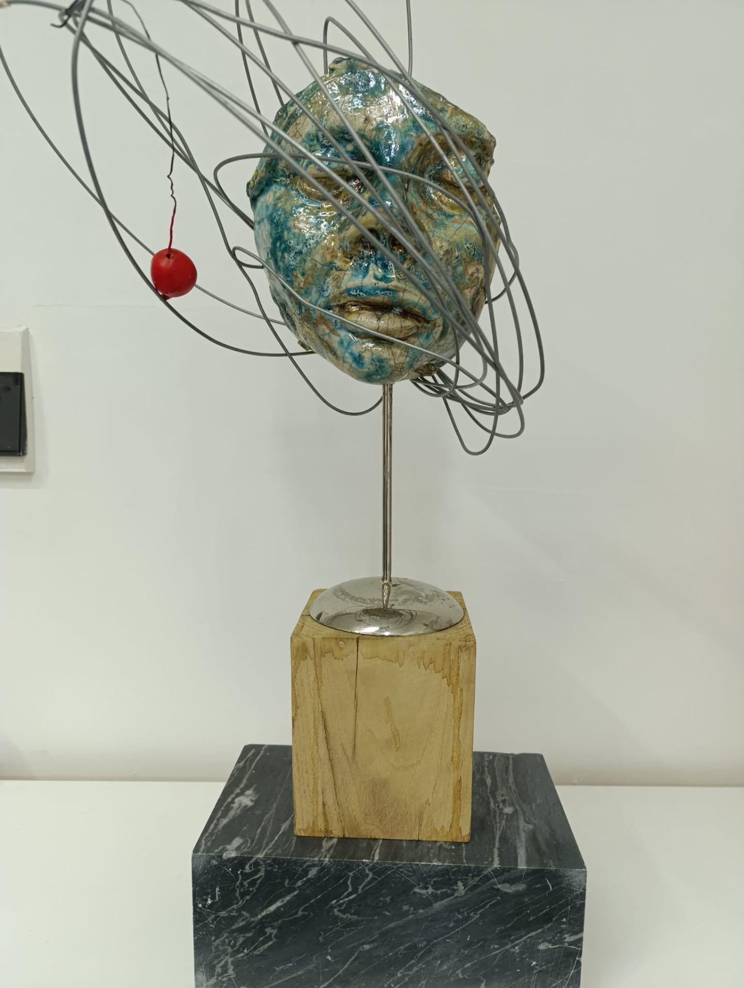 Volto Raku con smalti azzurri e sfera rossa orbitante