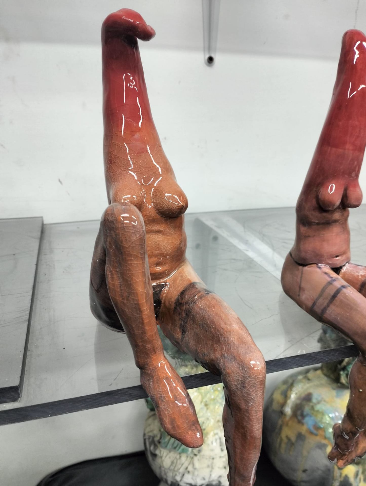 Figure femminili allungate sedute, ceramica craquelé rossa