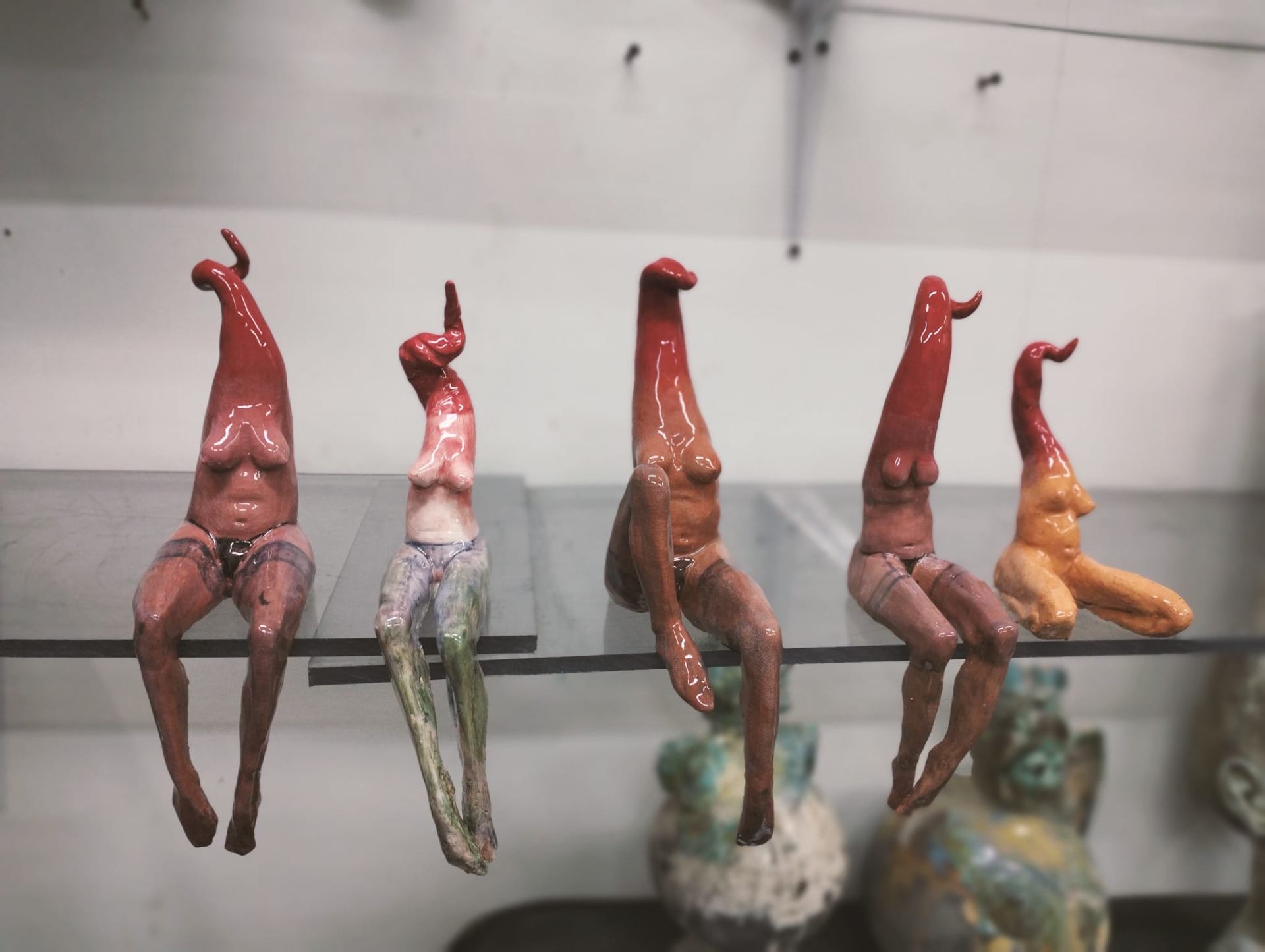 Cinque figure femminili sedute in fila, ceramica policroma