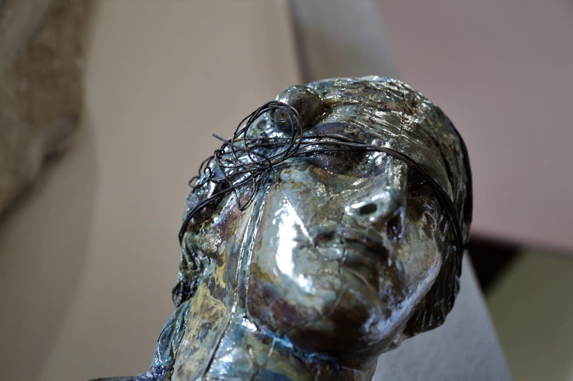 Dettaglio di volto Raku iridescente con filo metallico