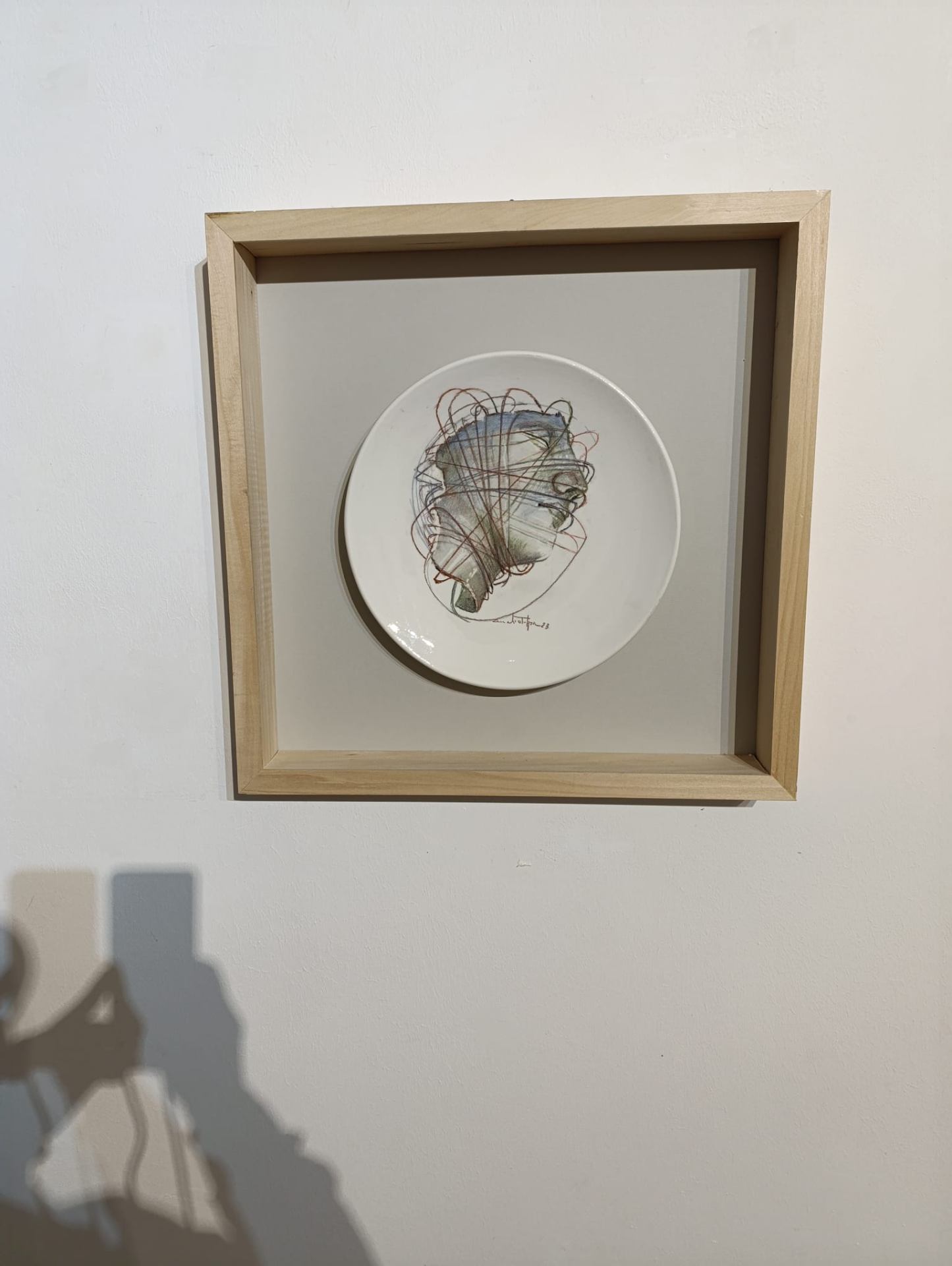 Piatto dipinto con volto, cornice in legno