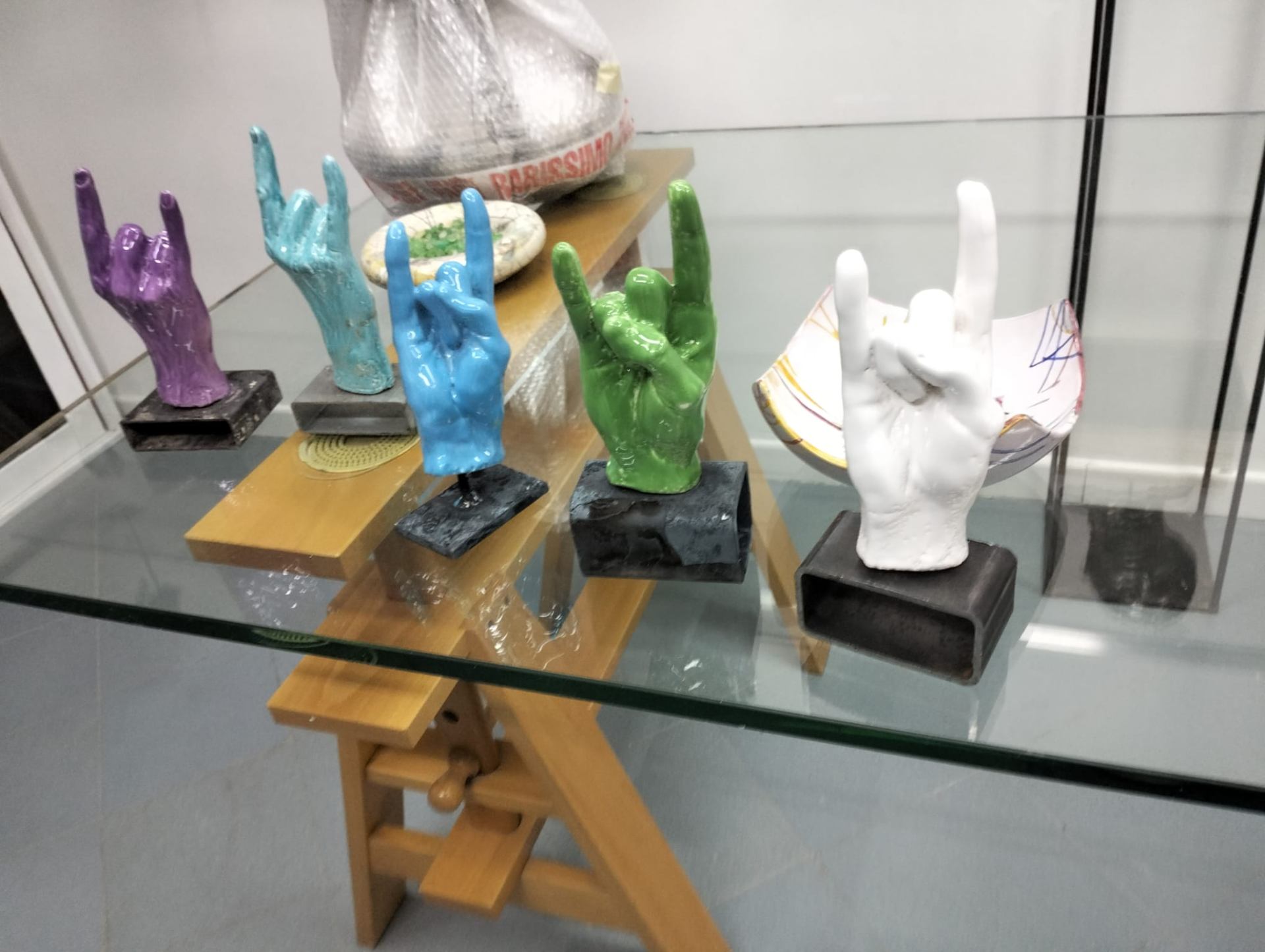 Sculture di mani in gesto rock in ceramica colorata